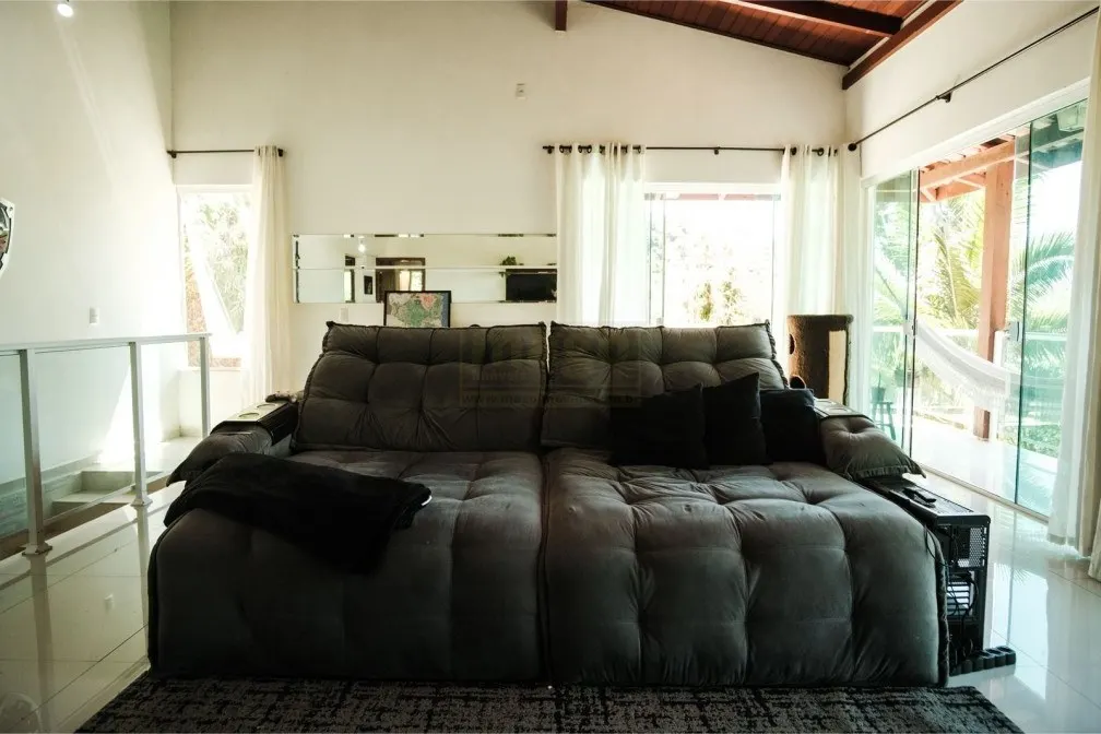 Sala com sofá e janelas para a mata