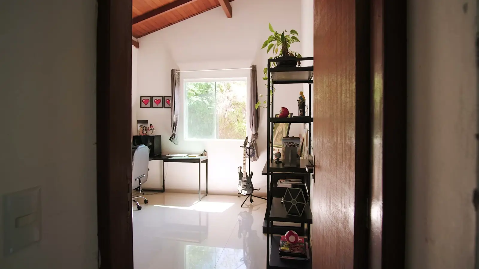 Quarto usado como escritório, com janela para as árvores